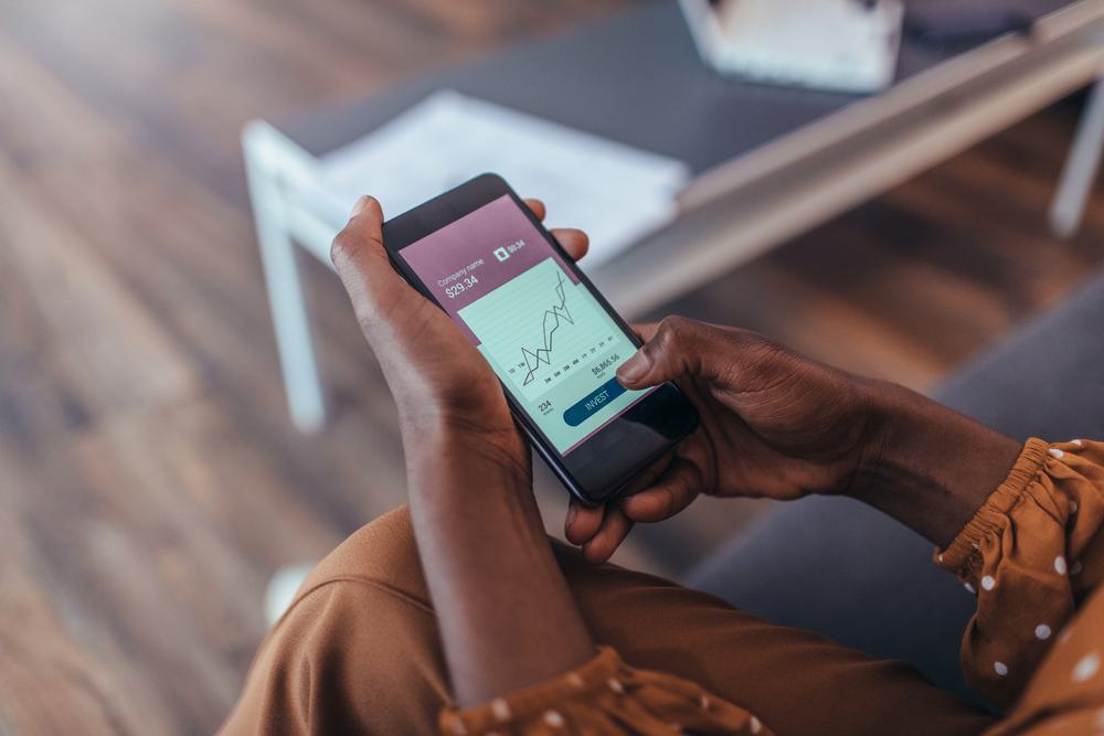 Hands using a mobile phone with a graph and numbers onscreen