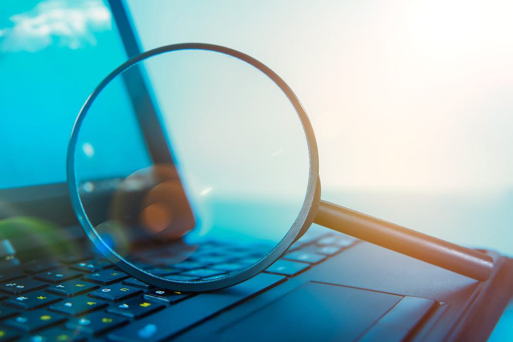 A magnifying glass resting on a laptop keyboard