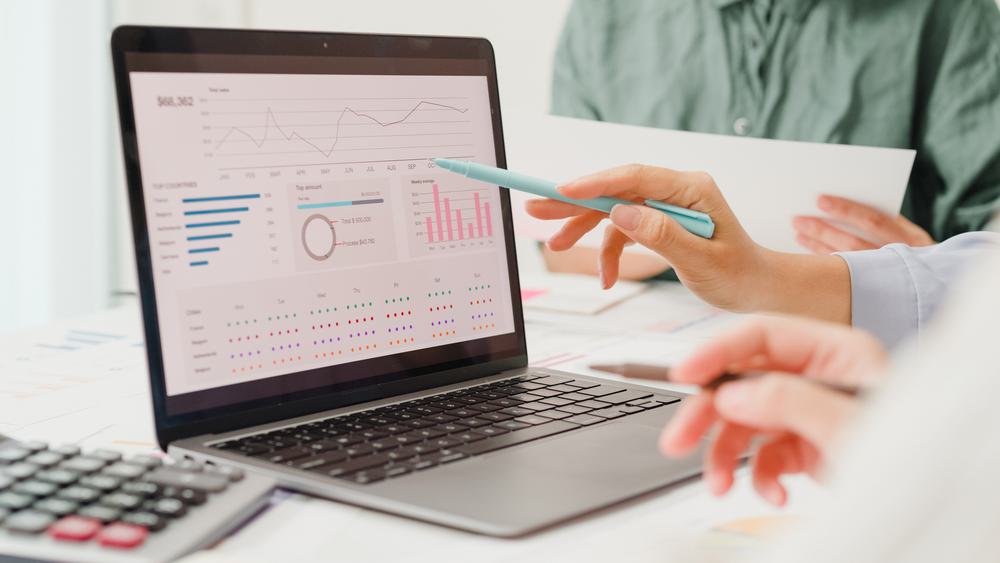 Hands gesturing at a laptop with analytics onscreen