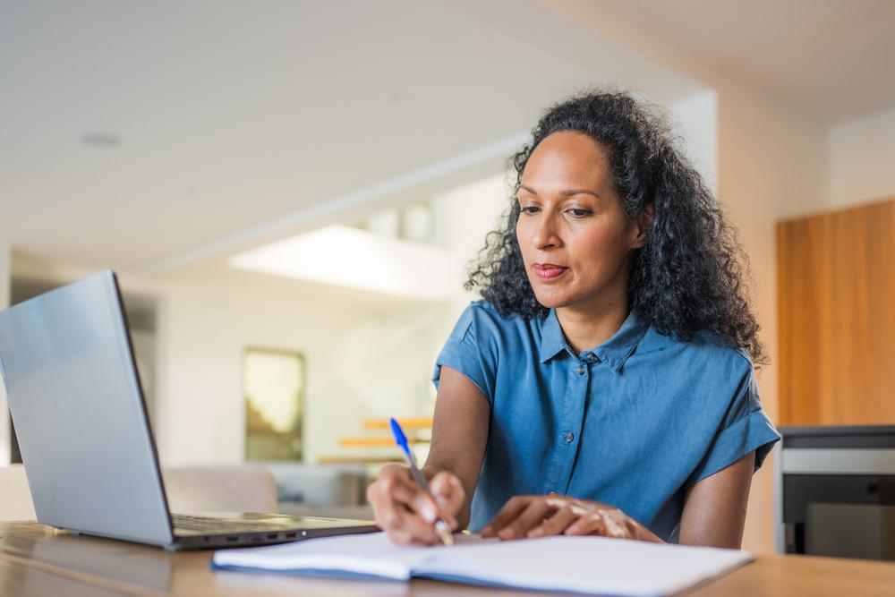 A woman taking notes from her laptop screen