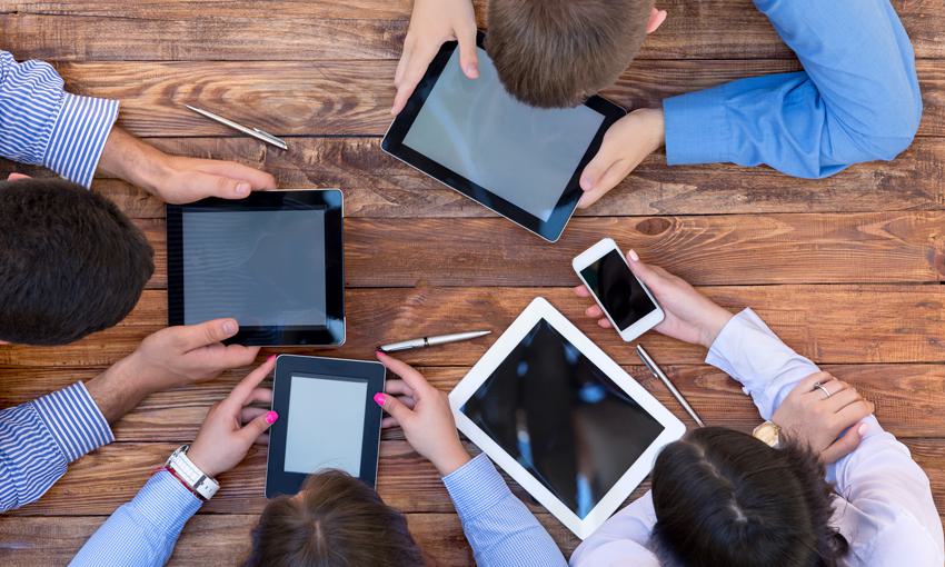 people huddled in a circle with ipads