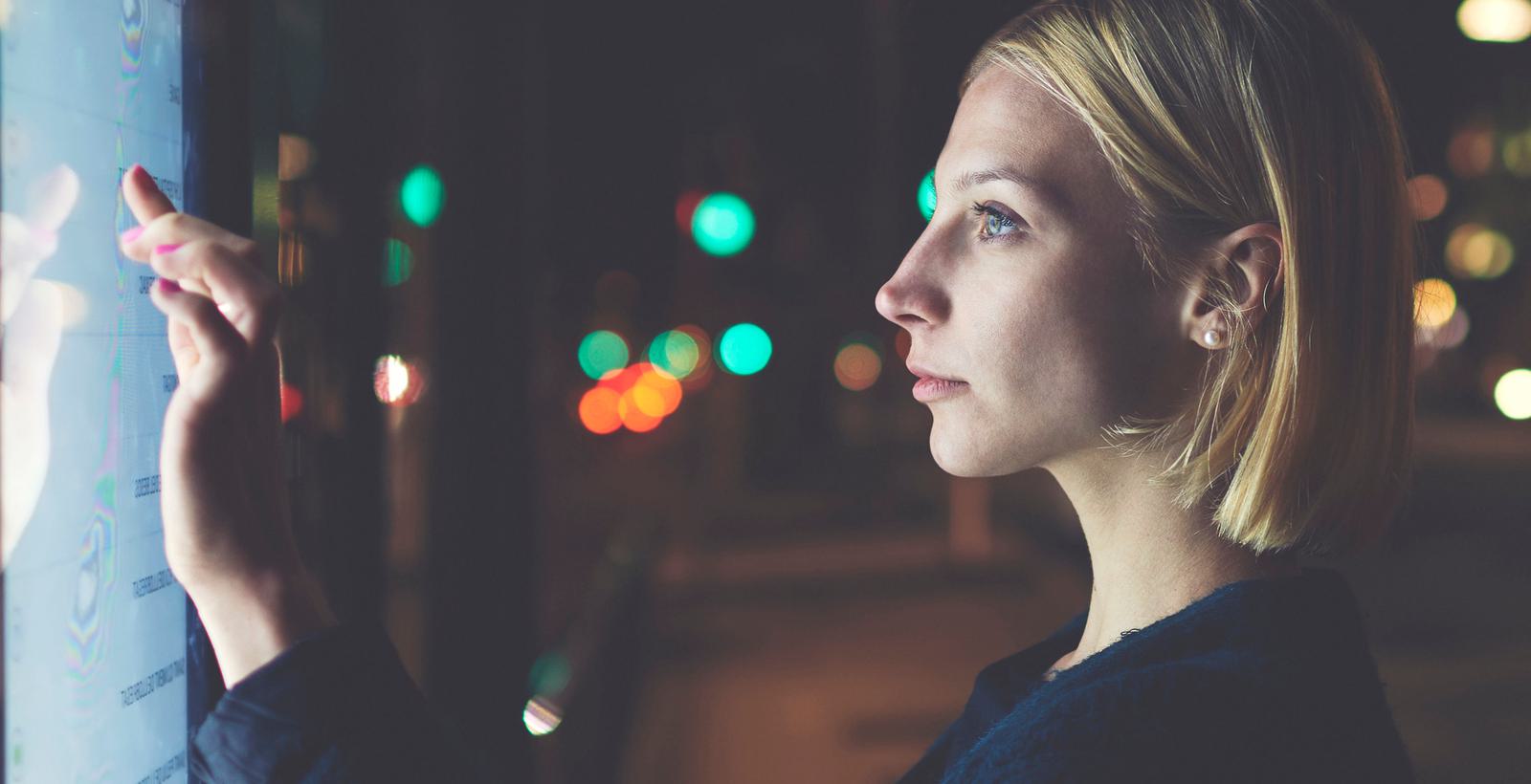 Woman touching a screen at night