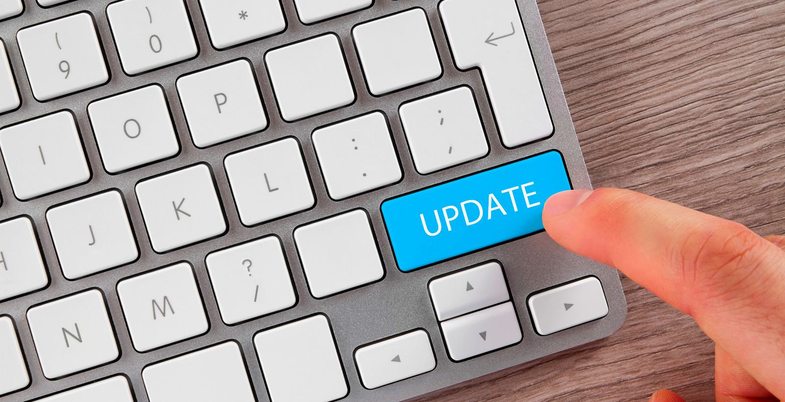 A keyboard with someone's finger hovering over the word UPDATE