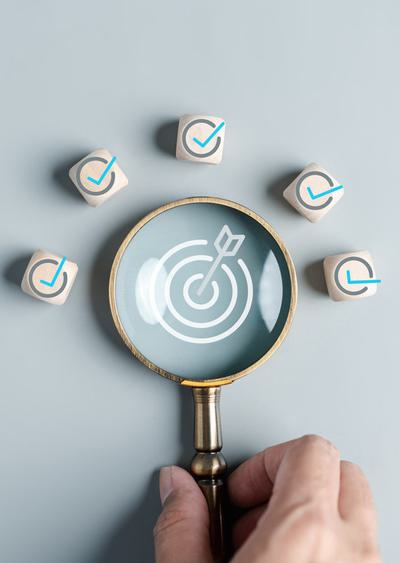 A magnifying glass with a bullseye and arrow in the centre, surrounded by tick icons.