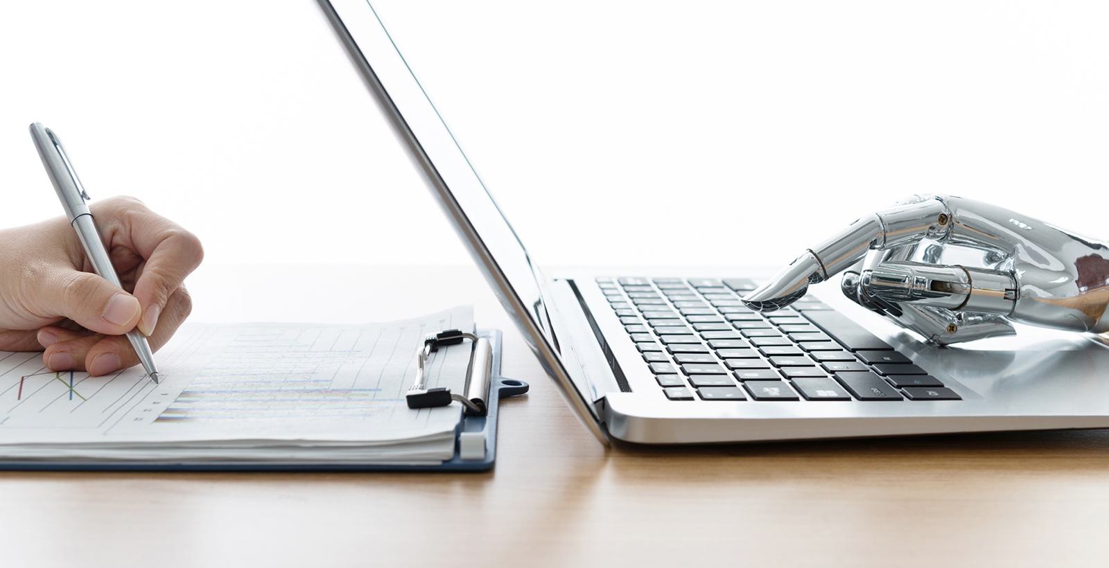 Robot hand using laptop and man hand writing