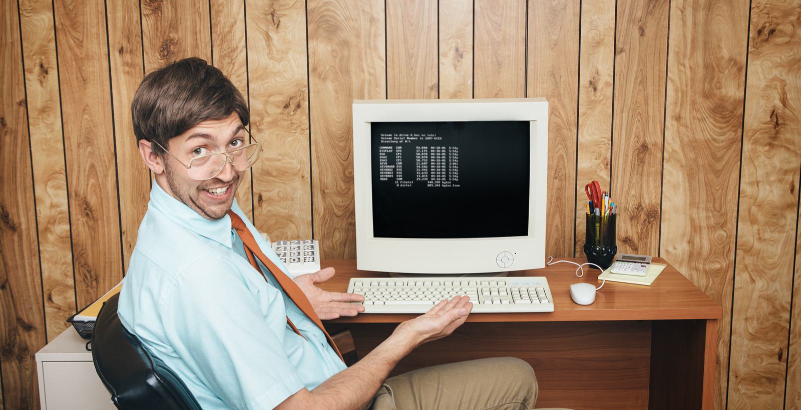 Man at old computer with glasses leaning back