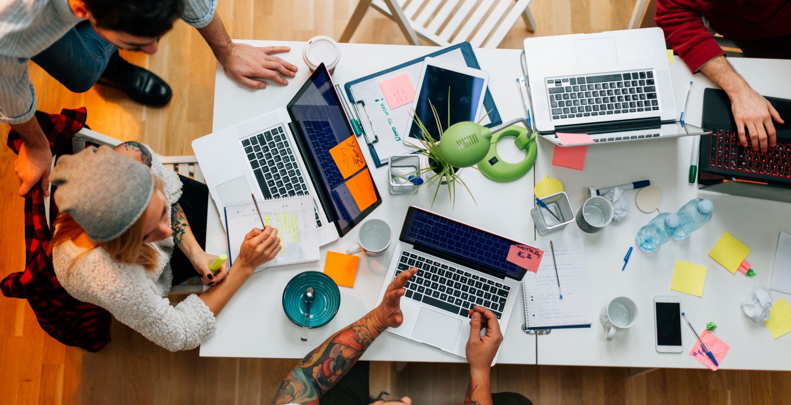 Overhead view of marketing team working at a desk with laptops